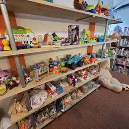 Houten stellingen vol met speelgoed, poppen, auto's en andere kinderartikelen in de kringloopwinkel