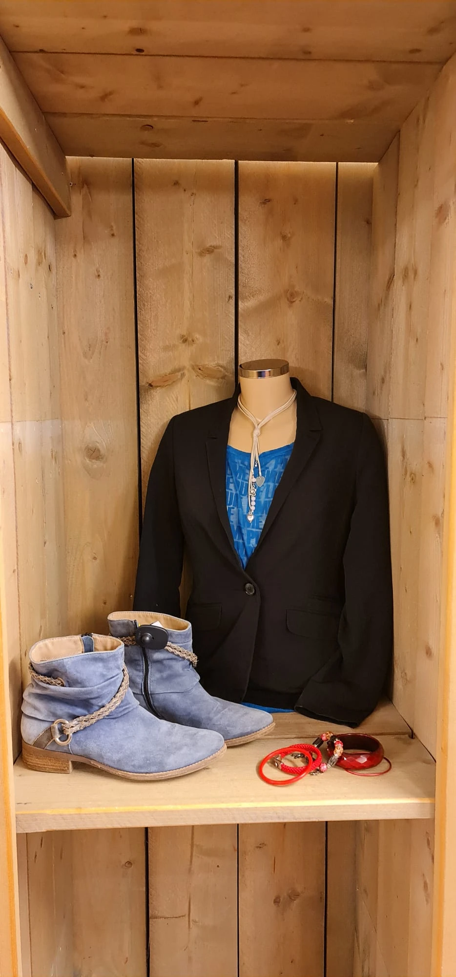 Zwart colbert op etalagepop met blauwe top en zilveren ketting eronder