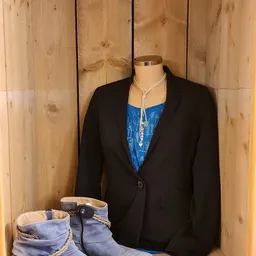 Zwart colbert op etalagepop met blauwe top en zilveren ketting eronder