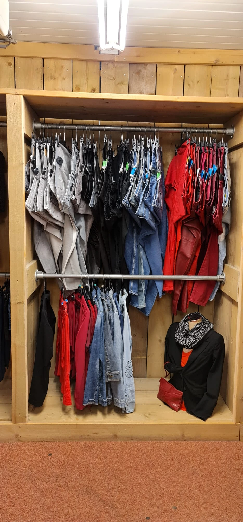 Kledingrek met tweedehands kleding in verschillende kleuren: grijs, zwart, blauw, rood en wit