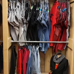 Kledingrek met tweedehands kleding in verschillende kleuren: grijs, zwart, blauw, rood en wit