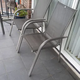 Grijze tuinstoelen op een terras naast een gebouw