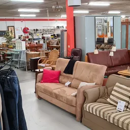 Bruine en beige banken en fauteuils met kussens uitgestald in de kringloopwinkel