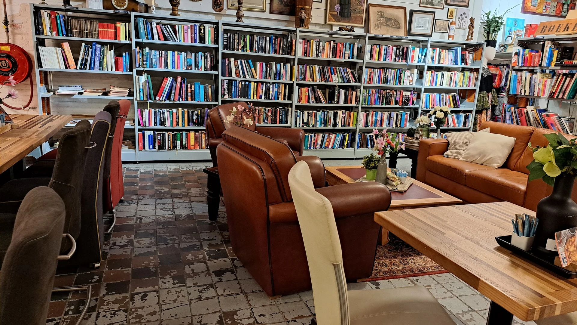 Leeshoek met bruine leren fauteuils, houten tafel en uitgebreide boekenkasten vol boeken aan de muur