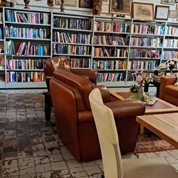 Leeshoek met bruine leren fauteuils, houten tafel en uitgebreide boekenkasten vol boeken aan de muur