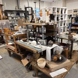 Winkelvloer met houten tafels en stellingen vol huishoudelijke spullen, servies en decoratieartikelen