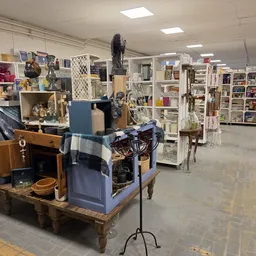 Winkelvloer van kringloopwinkel met diverse meubels, stellingen en huishoudartikelen uitgestald