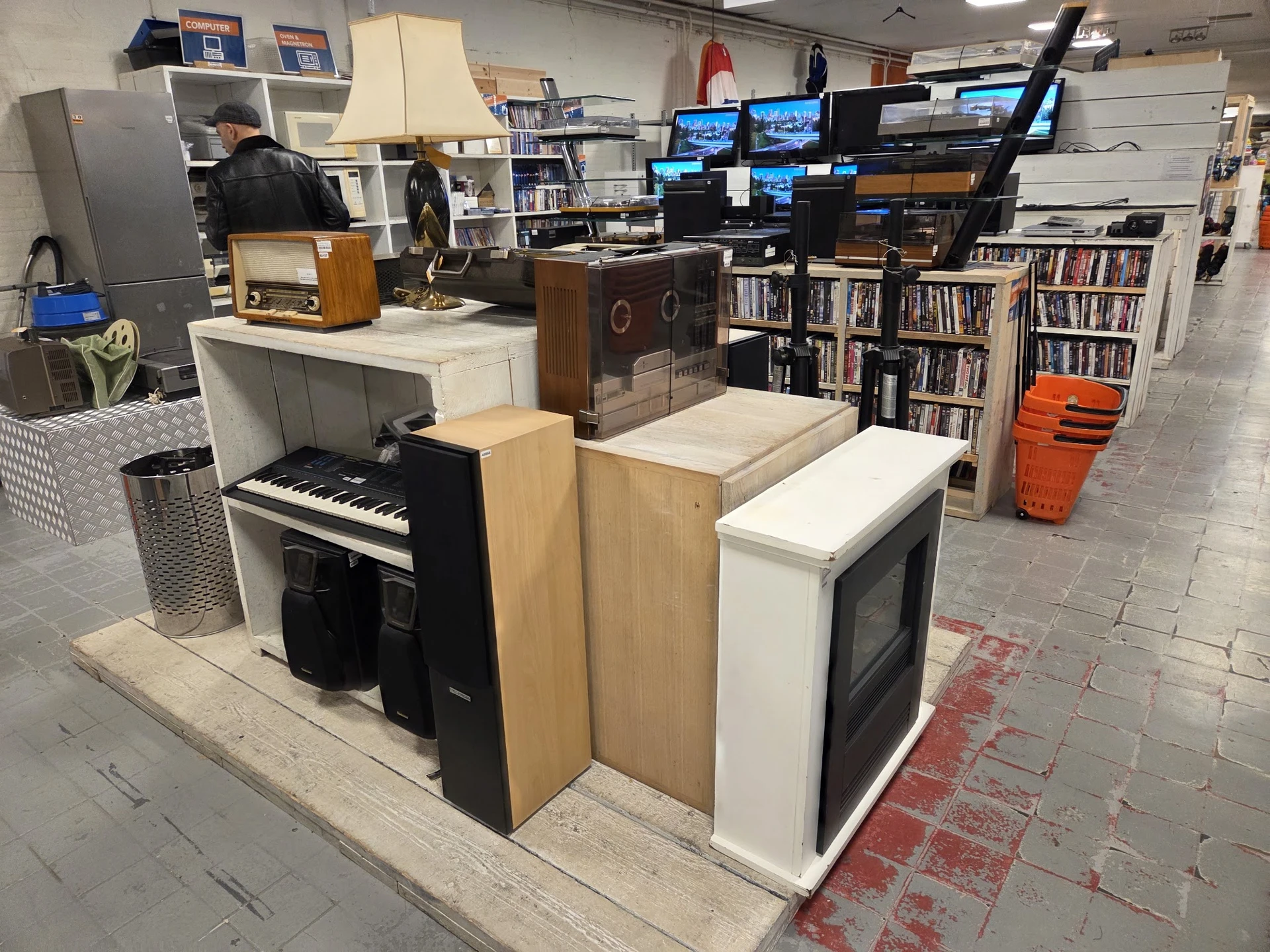 Winkelvloer met uitgestalde elektronica, muziekinstrumenten en boeken in stellingen