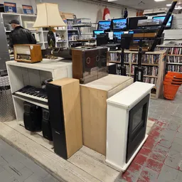 Winkelvloer met uitgestalde elektronica, muziekinstrumenten en boeken in stellingen