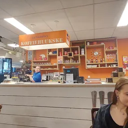 Koffiebalie 'Koffiehuiskje' met oranje stellingkast en bediening achter de balie