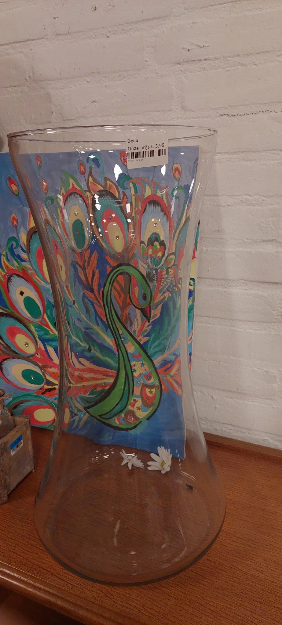 Close-up van een decoratief kunstwerk met pauwmotief in felle kleuren: rood, groen, blauw en goud