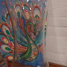Close-up van een decoratief kunstwerk met pauwmotief in felle kleuren: rood, groen, blauw en goud
