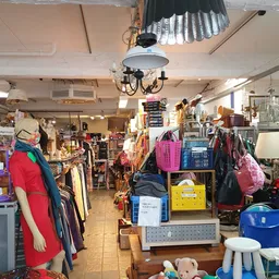 Winkelvloer met kledingrekken, toonbanken en diverse tweedehands artikelen uitgestald
