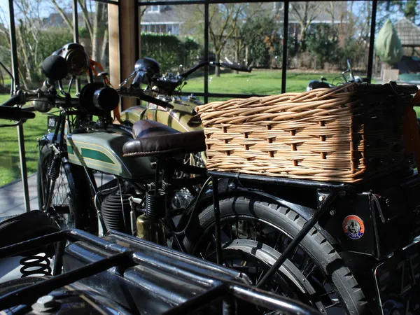 Vintage motorfiets met zijspan en rieten mand op uitstalling