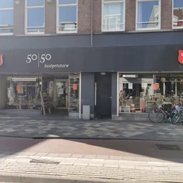 Gevel van Leger des Heils 50|50 Budgetstore aan Middenweg in Amsterdam met donkergrijze pui, winkelnaam zichtbaar, etalagerui