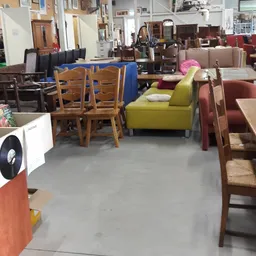 Winkelvloer met diverse meubels: houten stoelen, gele bank, rode fauteuils en andere zitmeubels uitgestald