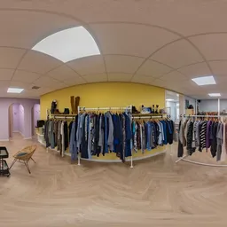 Ruim winkelbinnenland met gele kledingrek en rekken met tweedehands kleding, houten vloer en moderne plafondverlichting