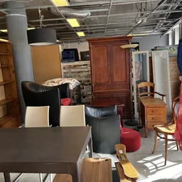 Winkelvloer met diverse meubels: tafels, stoelen, kasten, een rode zitzak en textielartikelen