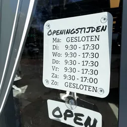 Openingstijdenbord met handgeschreven winkeluren op witte achtergrond
