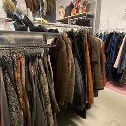 Rekken met tweedehands jassen en jacks in verschillende kleuren en materialen