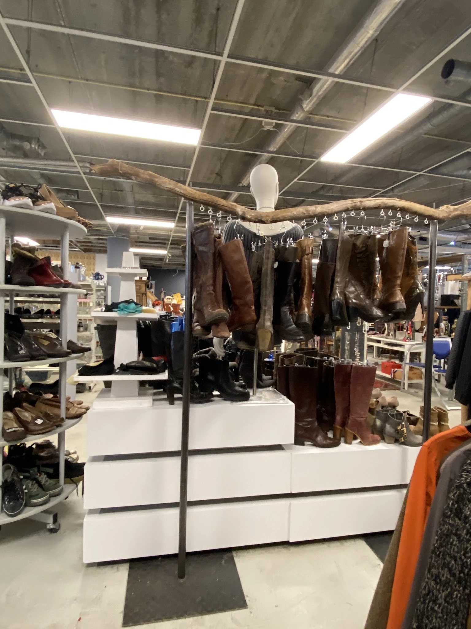 Uitgestalde laarzen en schoenen aan hangers en op stellingen in een kringloopwinkel