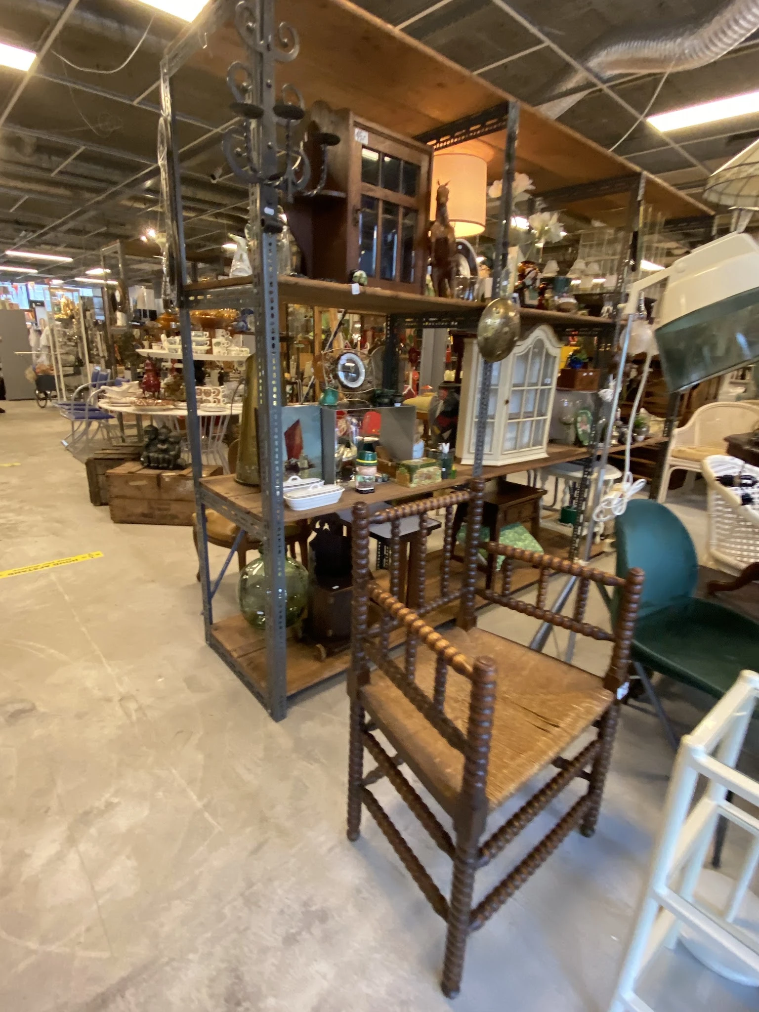Tweedehands meubelen en huishoudartikelen uitgestald in de kringloopwinkel, waaronder een tafel met stoelen en diverse decora