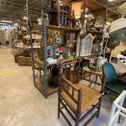 Tweedehands meubelen en huishoudartikelen uitgestald in de kringloopwinkel, waaronder een tafel met stoelen en diverse decora