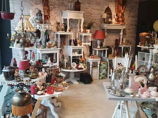 Winkelvloer met wit stellingwerk vol decoratieve artikelen, lampen, vazen, beelden en vintage spullen tegen bakstenen muur