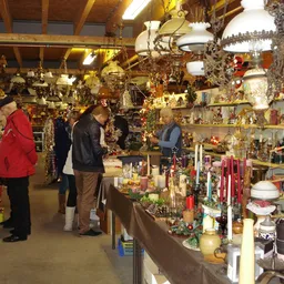 Winkelinterieur met bezoekers tussen stellingen vol decoratie-artikelen, kerstversiering en huishoudspullen