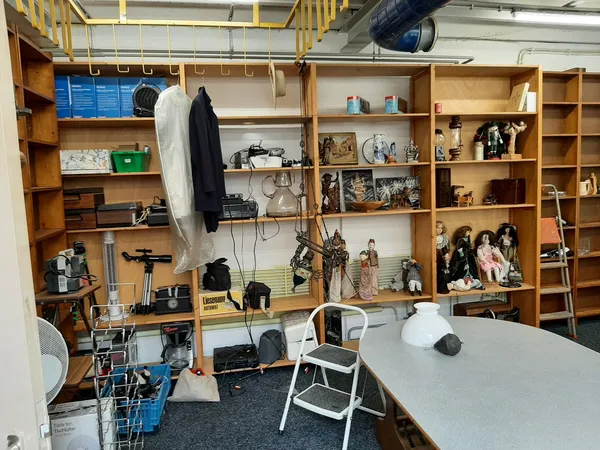 Kringloopwinkel met houten stellingen vol huishoudelijke spullen, decoraties en diverse tweedehandsartikelen