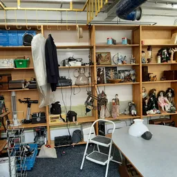 Kringloopwinkel met houten stellingen vol huishoudelijke spullen, decoraties en diverse tweedehandsartikelen