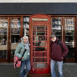 Twee personen poseren voor een rode Britse telefooncel voor een winkel