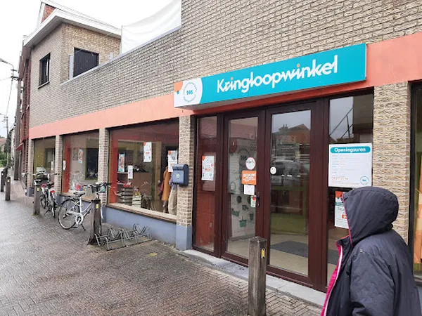 Gevel van kringloopwinkel met turquoise en oranje bord, bruine deuren en ramen, fietsen ervoor