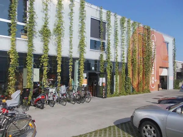Moderne gevel met verticale groene beplanting en rood accent, fietsen geparkeerd ervoor