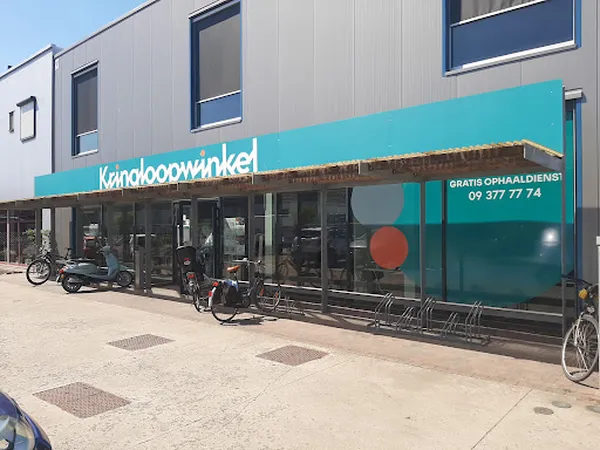 Winkelgevel met turquoise luifel en donkergroene etalage, winkelnaam leesbaar, fietsen geparkeerd ervoor