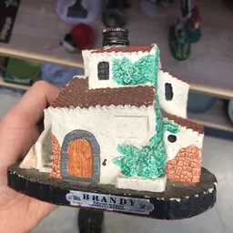 Beschilderd keramiek huisje met groene en bruine details op zwart voetje