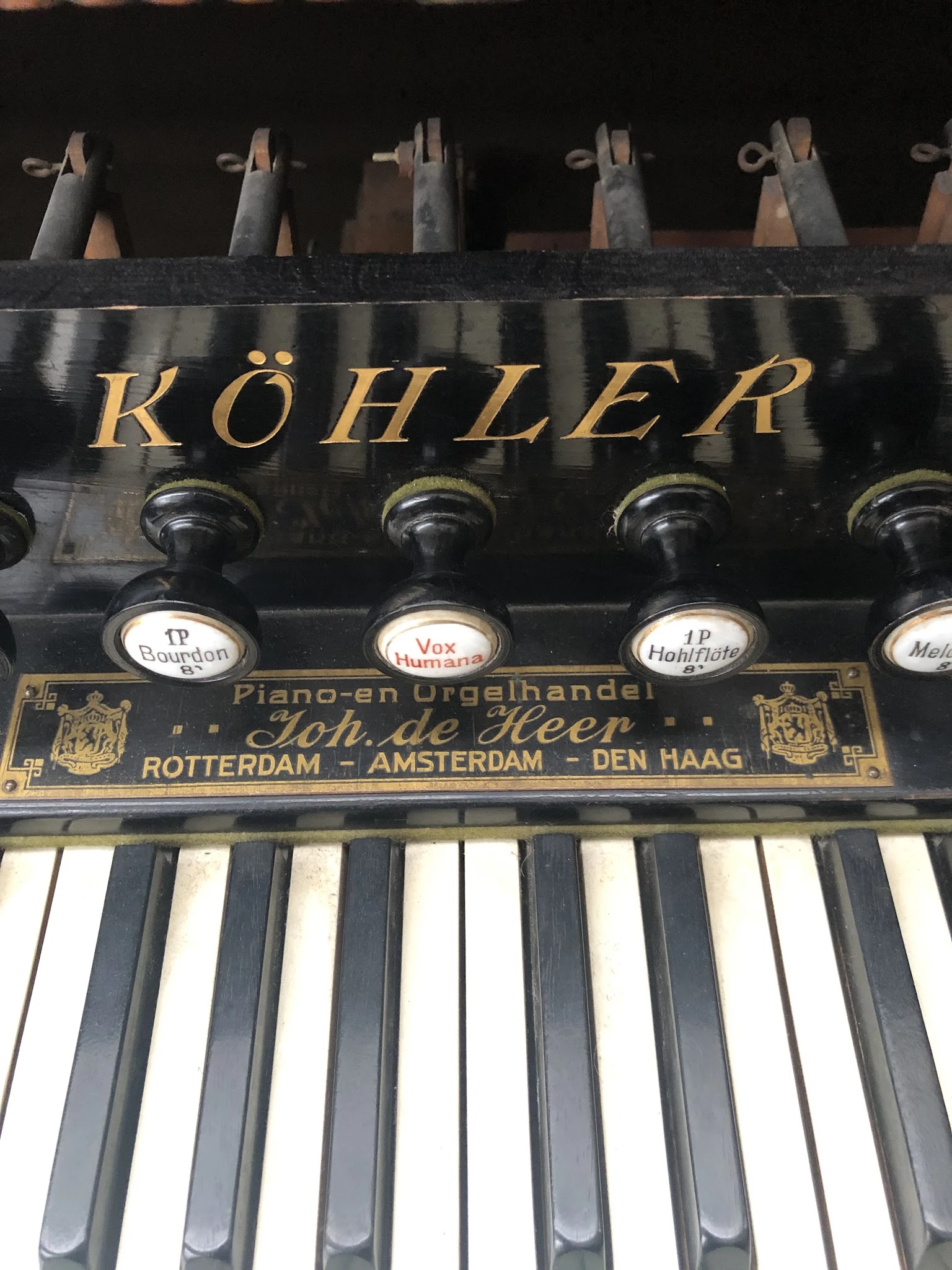 Close-up van een Köhler piano-orgel met toetsen en registerknopen met labels