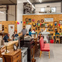 Overzicht van kringloopwinkel met meubels, decoratie en gasten die rondkijken
