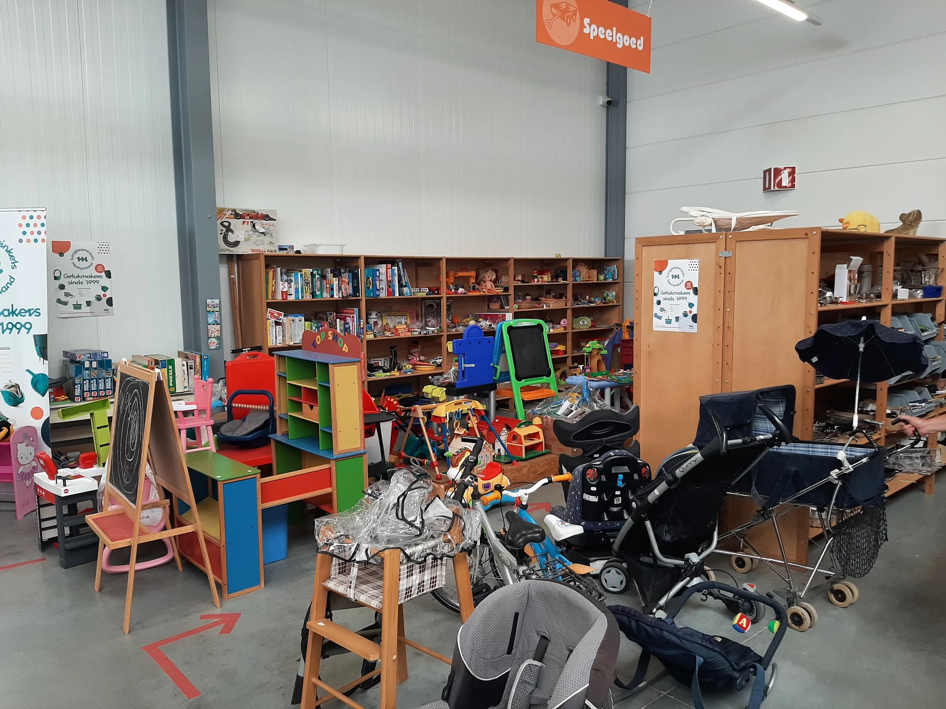 Winkelvloer met speelgoed, kinderstoeltjes, boeken, kasten en kinderwagens in kringloopwinkel