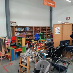 Winkelvloer met speelgoed, kinderstoeltjes, boeken, kasten en kinderwagens in kringloopwinkel