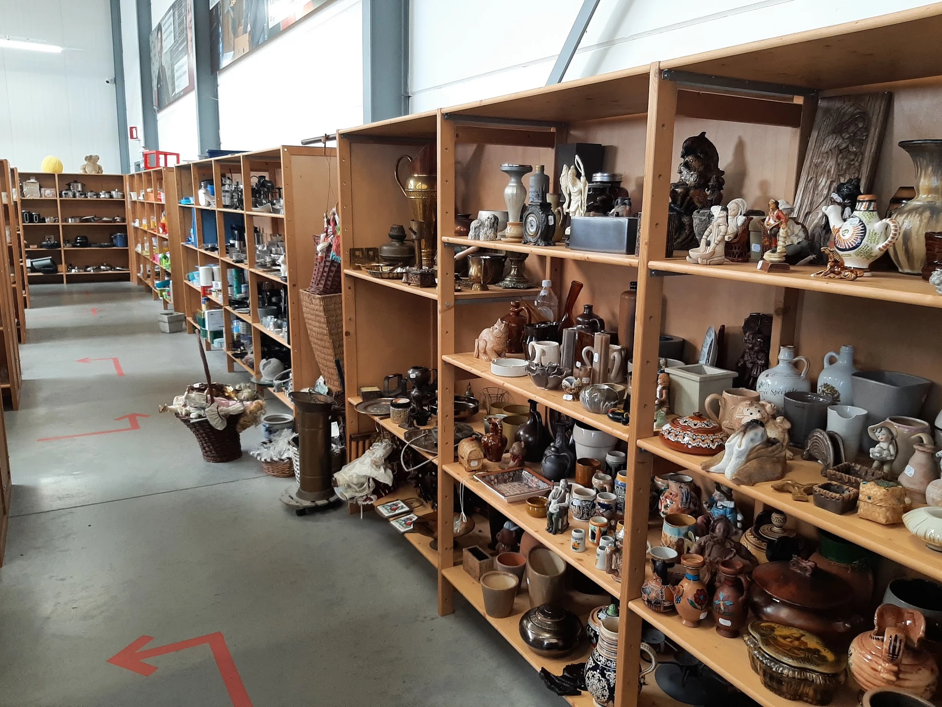 Houten stellingen met uitgestalde decoratieve artikelen, beeldjes, servies en antieke spullen in een kringloopwinkel