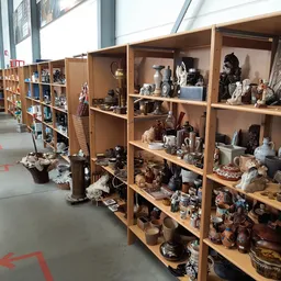 Houten stellingen met uitgestalde decoratieve artikelen, beeldjes, servies en antieke spullen in een kringloopwinkel