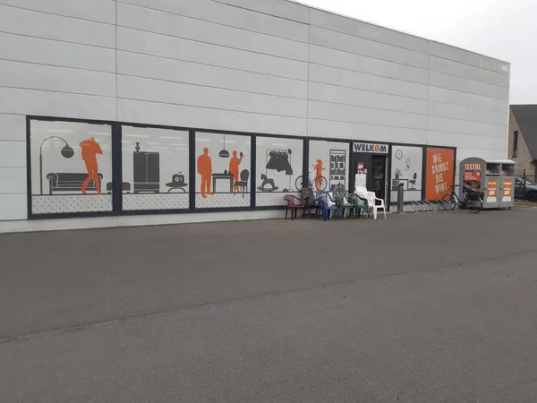 Gevel van kringloopwinkel met grote etalagevensters metDisplayfiguren en tweedehands huishoudelijke artikelen