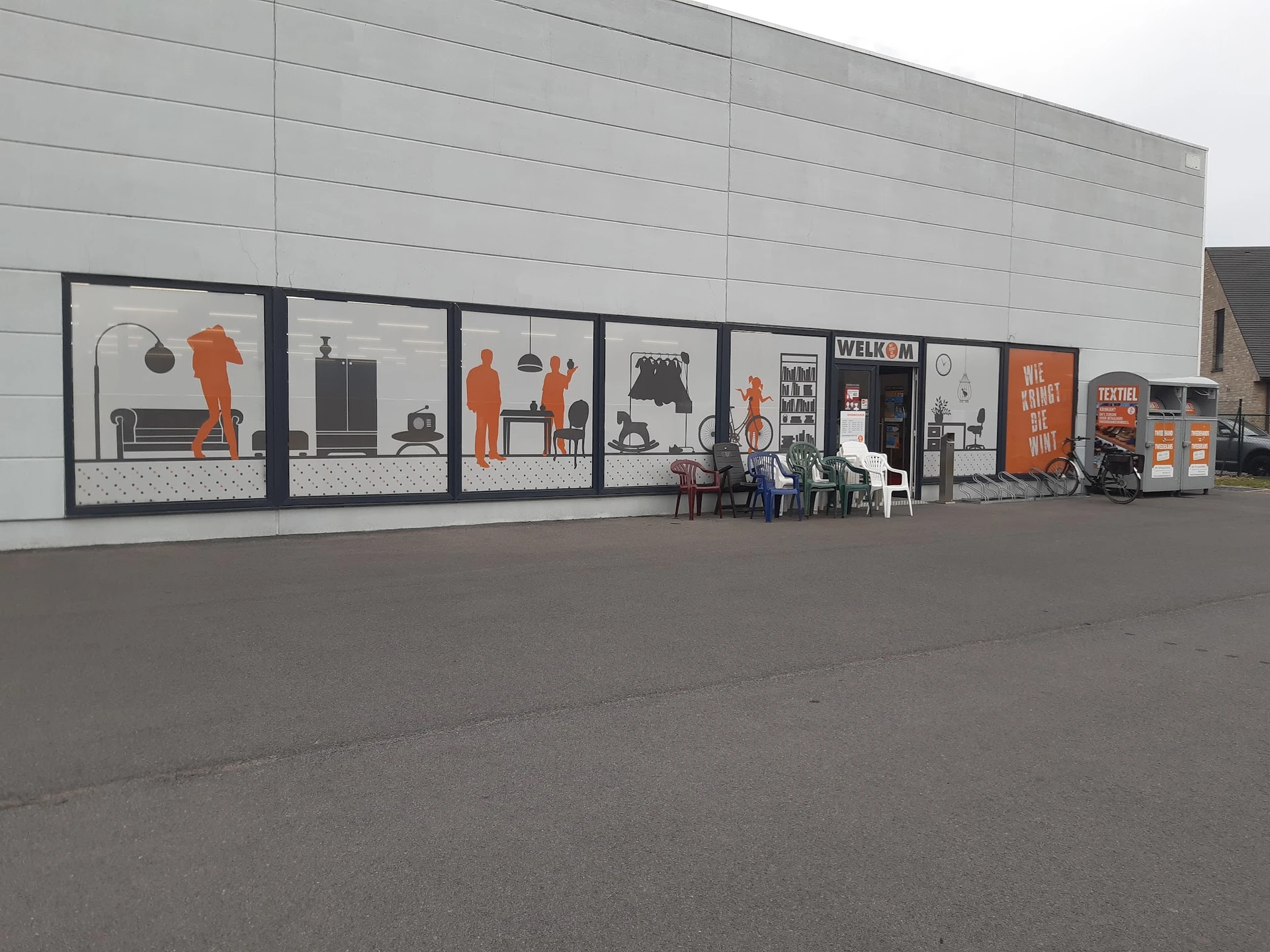 Gevel van kringloopwinkel met grote etalagevensters metDisplayfiguren en tweedehands huishoudelijke artikelen