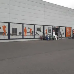 Gevel van kringloopwinkel met grote etalagevensters metDisplayfiguren en tweedehands huishoudelijke artikelen