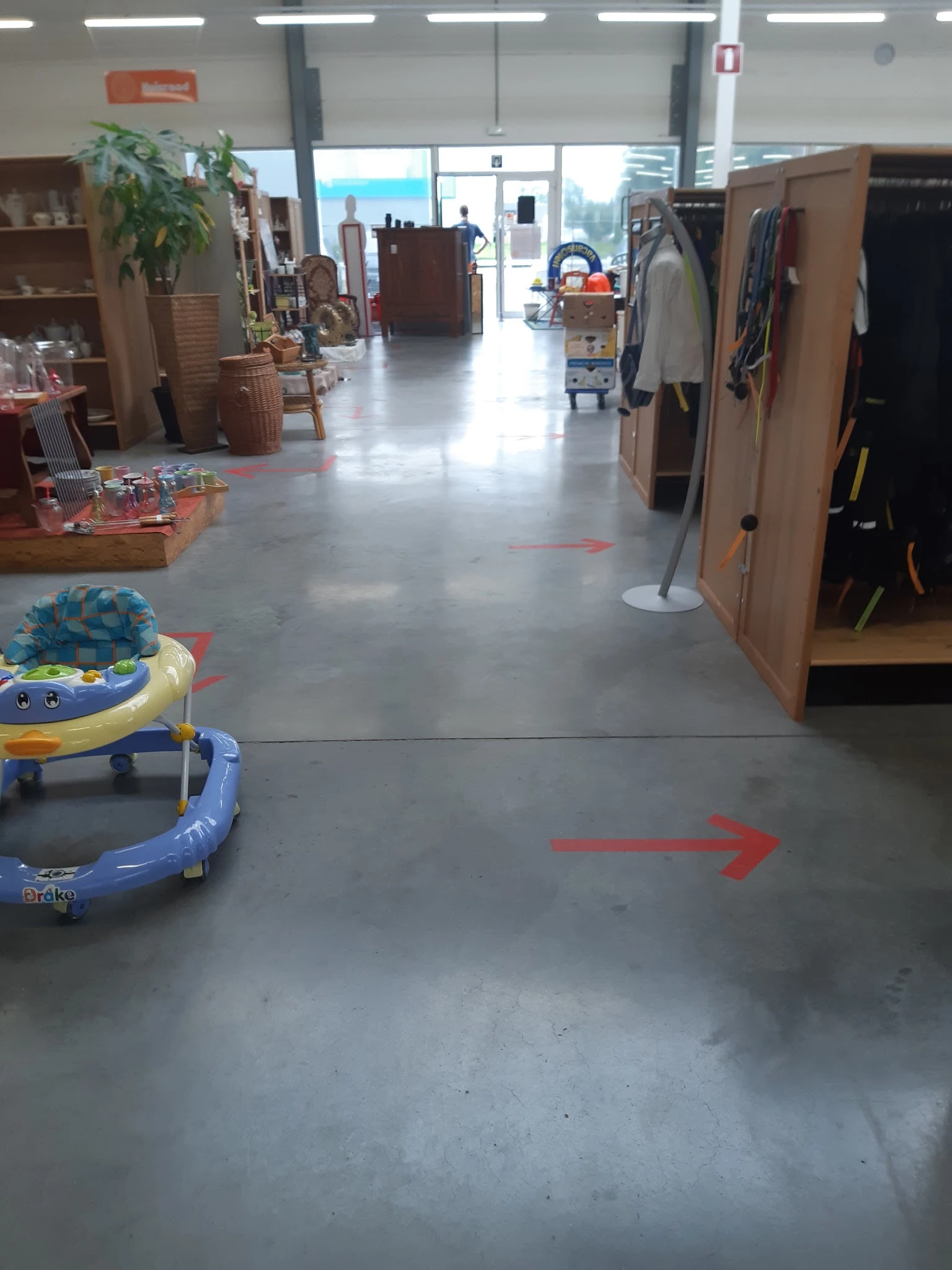 Winkelvloer met rode pijlen als richtlijnen, babyspeelgoed links, kasten en rekken met spullen langs de zijkanten