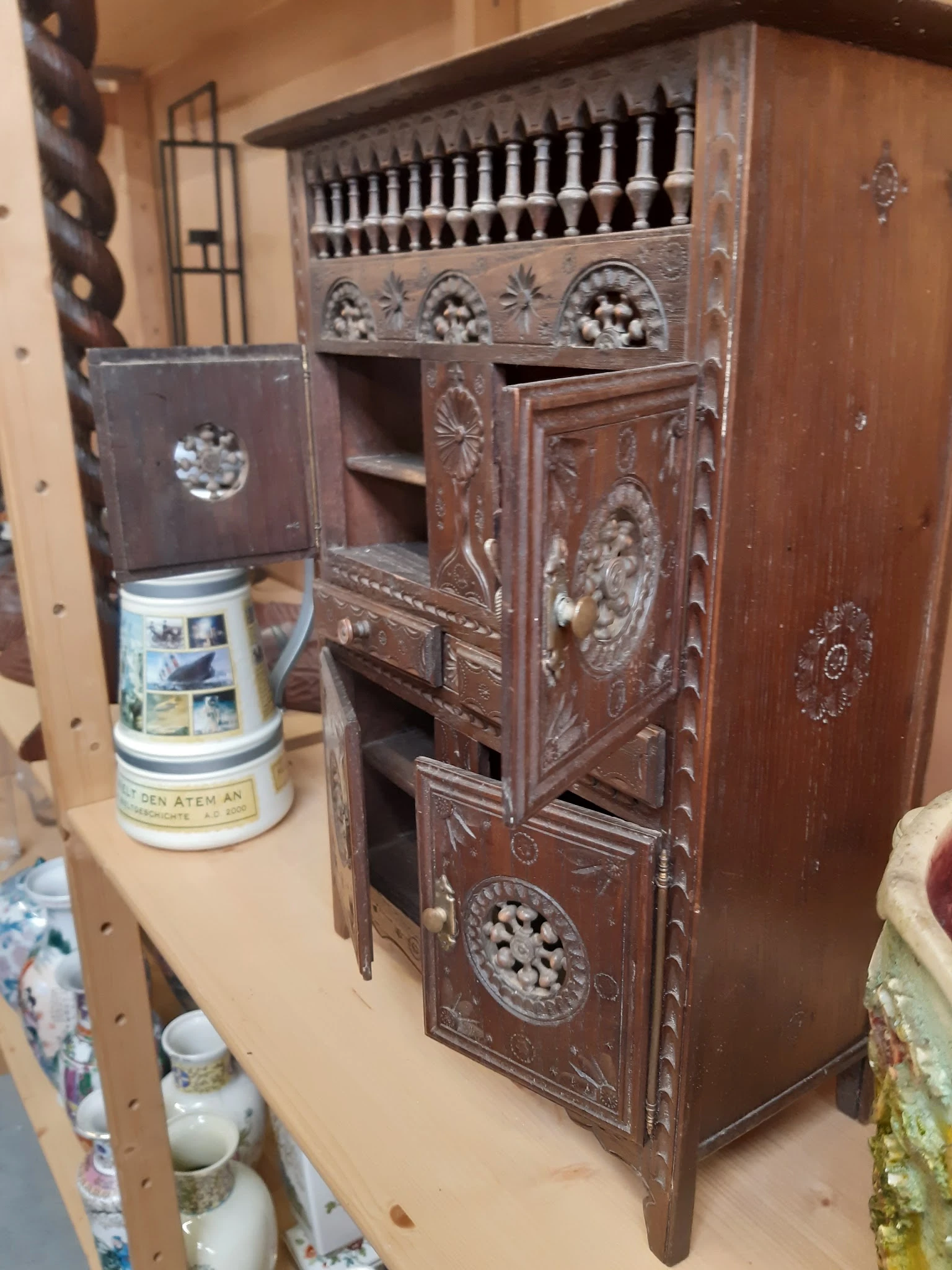 Houten kastje met decoratieve snijwerk en een keramische pot ernaast