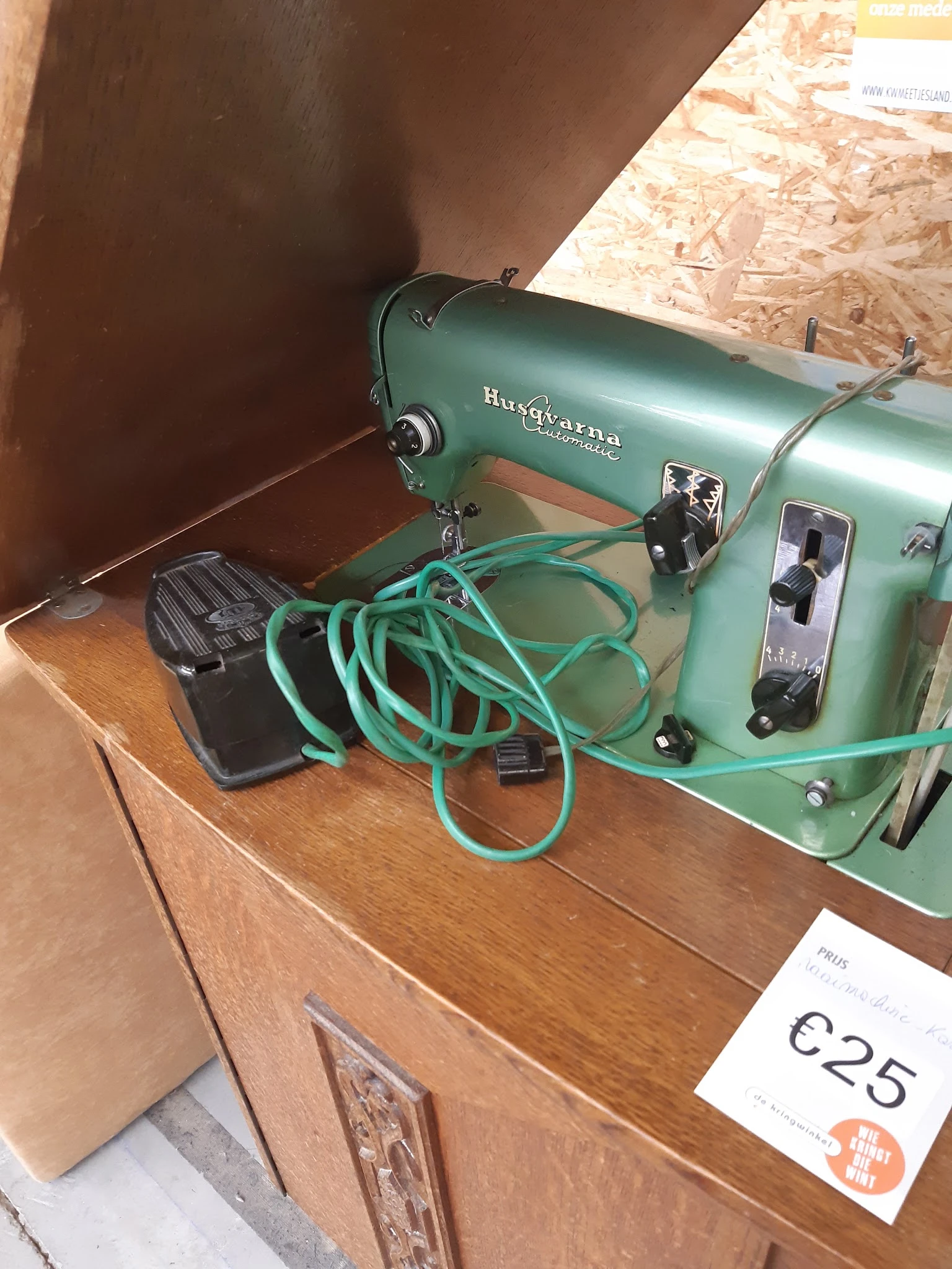 Groene vintage naaimachine Husqvarna met turquoise snoer op houten tafel