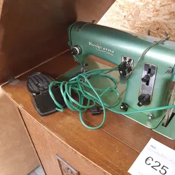 Groene vintage naaimachine Husqvarna met turquoise snoer op houten tafel