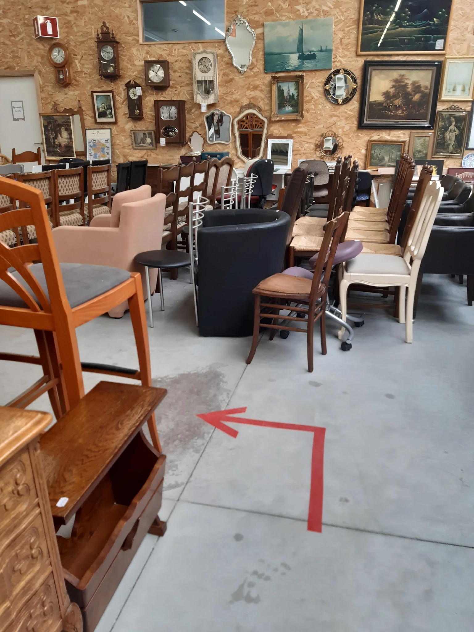 Winkelvloer met diverse meubels: houten stoelen, fauteuils, tafels en kasten met framed afbeeldingen op achtergrond